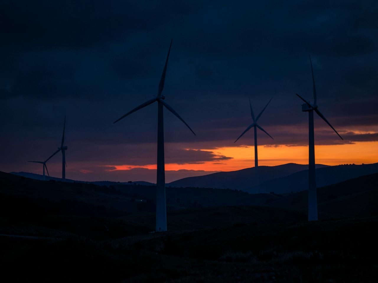 On-shore wind turbines silhouetted against a sunset